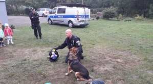 Chłopiec w obecności policjanta i psa służbowego prezentuje tak zwaną pozycję żółwia