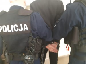 policjanci prowadza zatrzymanego wandala do zniszczenia pomnika Jana Pawła II