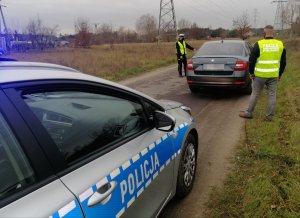 Policjanci podczas kontroli świateł w pojazdach  na polnej drodze, na trasie oraz w salonie biorącym udział w akcji Skoda w Lubiczu podczas ustawiania świateł przez diagnostę.