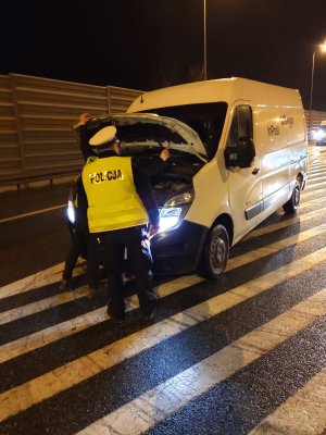 Policjanci podczas kontroli świateł w pojazdach  na polnej drodze, na trasie oraz w salonie biorącym udział w akcji Skoda w Lubiczu podczas ustawiania świateł przez diagnostę.