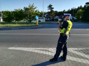 kontrola drogowa, policjant z miernikiem prędkości stoi przy drodze