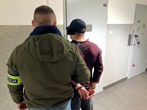 nieumundurowany funkcjonariusz doprowadza zatrzymanego do policyjnej celi